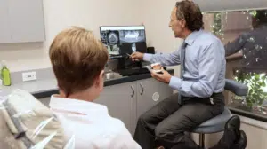 Dr. Farris points to an X-ray on a computer screen while talking with a patient.