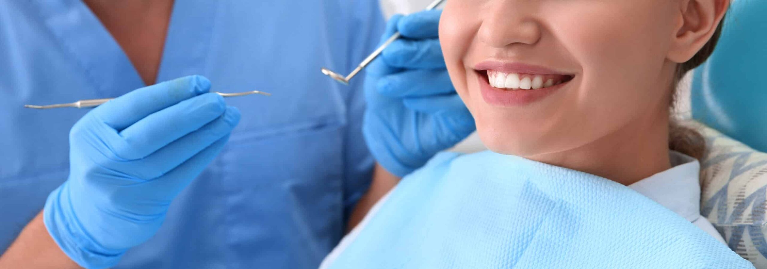 dentist holding dental tools while patient smiles
